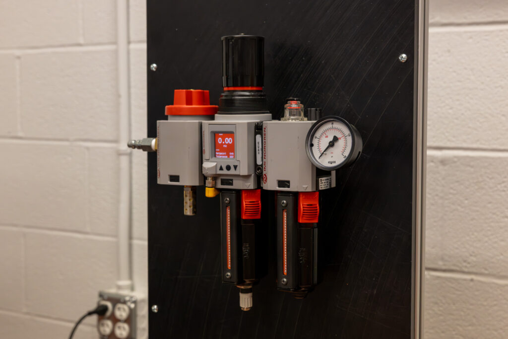 Industrial control valve unit with two red-handled levers, a round pressure gauge, and a digital readout showing 0.00 psi mounted on a black panel.